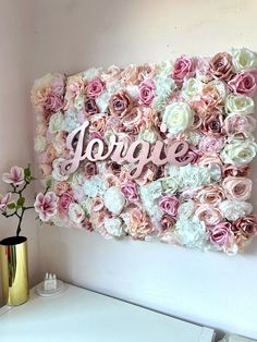 a pink and white flowered wall with the word love spelled on it