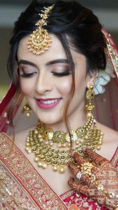 a woman in a red and gold bridal outfit with her hands on her chest