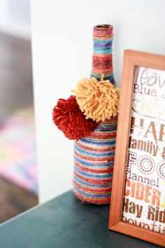 a bottle with some yarn on it sitting next to a framed photograph and a frame