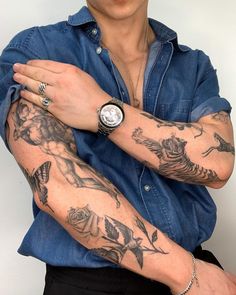 a man with tattoos on his arm and wrist is posing for the camera while wearing a blue shirt