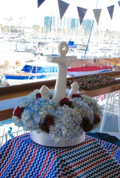 a table with flowers and an anchor on it at a boat show in the water