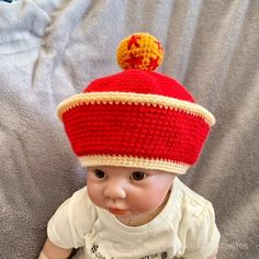 a baby wearing a red and yellow knitted hat