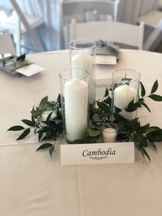 candles and greenery are arranged on the table