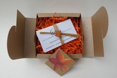 an open box with a tag and some orange shredded carrots in it, sitting on a white surface