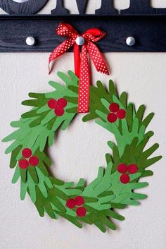 a christmas wreath made out of paper on a door hanger with red ribbon and bow