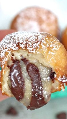 a half eaten chocolate covered doughnut with powdered sugar on it's end