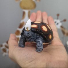 a hand holding a small toy turtle with a light on it's head