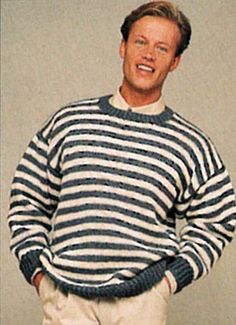 a man wearing a striped sweater and khaki pants with his hands in his pockets