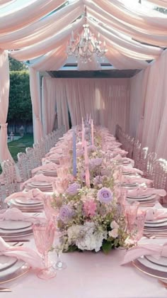 the table is set with pink and white flowers, silverware, candles, and napkins