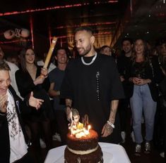 a man standing in front of a cake with candles on it and people around him