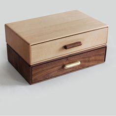 a wooden box sitting on top of a white table next to a brown drawer with gold handles