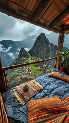 a bed sitting on top of a wooden floor next to a lush green mountain covered in clouds