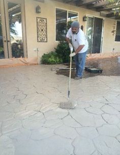 a man is using a mop to clean the concrete on his driveway in front of a house