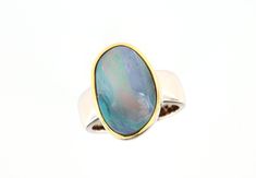 A simple, classic opal ring crafted in solid sterling silver. The ring has an Australian boulder opal from Queensland with a light blue-turquoise fire. There is also a red line running through the stone, which makes the boulder opal glow. The setting edge is gold-plated so that the stone is beautifully highlighted. The silver ring shank is 7-5.5mm wide.  Opal type: Boulder opal Origin/Place of discovery: Queensland, Australia Carat weight: 8.70ct, 20.5x15mm Metal: 925 silver, gold-plated setting Oval Opal Rings With Polished Finish, Formal Hallmarked Opal Ring, Modern Oval Opal Ring, Opal Rings With Polished Finish For Formal Occasions, Modern Opal Ring For Anniversary, Formal Opal Rings With Polished Finish, Formal Opal Ring With Polished Finish, Modern Oval Cabochon Opal Ring As Gift, Opal Open Ring With Polished Finish For Anniversary