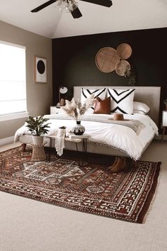 a bedroom with a bed, rug and ceiling fan in the corner is decorated with black and white accents