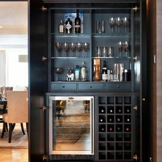 a black cabinet with wine glasses and bottles on it's doors is open to the dining room