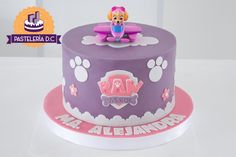 there is a purple cake with paw patrol decorations on the top and paws around the edges