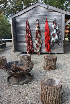 there are many umbrellas hanging on the side of this shed with firewood logs