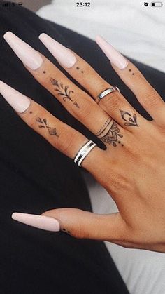 two hands with different tattoos and rings on them