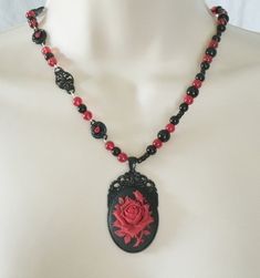 "Red Rose Necklace This beautiful necklace has red glass beads, black glass beads, seed beads, black metal connectors with rhinestones, black metal chain and a black metal pendant with resin rose. 20\" long. Lobster clasp." Gothic Beaded Jewelry Gift, Gothic Beaded Jewelry For Gift, Gothic Beaded Necklace For Gift, Black Necklace With Rose Design As Gift, Black Necklace With Rose Design For Gift, Antique Black Beaded Necklaces, Gothic Black Bead Necklace For Gift, Gothic Black Beads Necklace For Gift, Antique Black Beaded Necklace