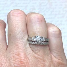 a woman's hand with a diamond ring on top of her finger and an engagement band