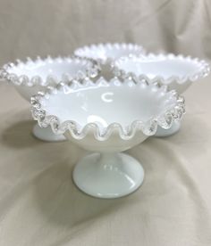 two white dishes sitting on top of a table next to each other with beaded trim