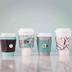 four coffee cups are lined up in different colors and designs, one has a button on the side