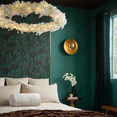 a bedroom with green walls and white flowers on the headboard, along with a chandelier