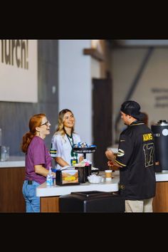 three people standing at a counter talking to each other