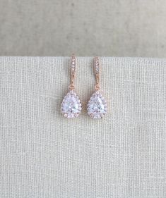 a pair of diamond earrings sitting on top of a piece of cloth