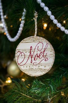 a wooden ornament hanging from a christmas tree with musical notes on it and the word noel written in red