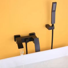 two black faucets are attached to the wall next to a white bathtub