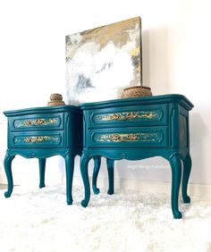 two blue nightstands with gold paint on them and a painting hanging above the top