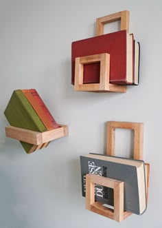 three wooden bookshelves mounted to the wall, each with different colored books on them