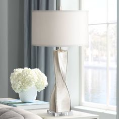 a lamp that is sitting on a table next to a vase with flowers in it