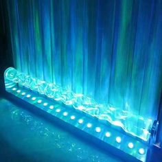 a water fountain with blue lights in front of curtained windows and curtains behind it