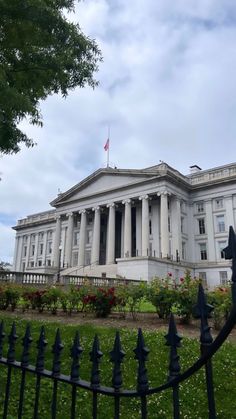 the white building has columns and pillars on it's sides, along with a wrought iron fence