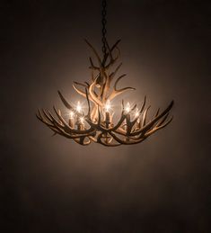 a chandelier made out of antlers hanging from a chain in the dark