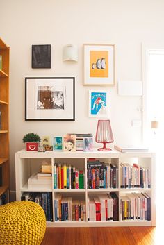 a living room with bookshelves and pictures on the wall