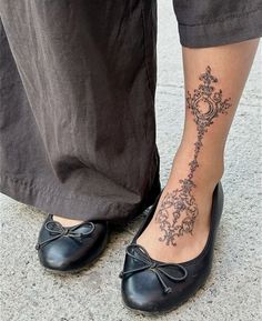 a woman's foot with a tattoo on her left leg and an ornate design on the ankle