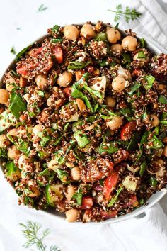 a white bowl filled with lots of food on top of a table next to a napkin