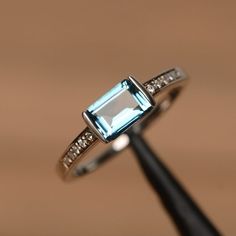 It is a London blue topaz ring. The main stone is 5mm*7mm emerald cut.The basic metal is sterling silver and plated with rhodium.To change the metal to a solid gold (white/rose) or platinum is also available, please ask for a quotation if you want.You can also go to my shop Home for more elegant rings: https://www.etsy.com/shop/godjewelry?ref=hdr_shop_menuTopaz is November birthstone.More topaz rings:https://www.etsy.com/shop/godjewelry?ref=hdr_shop_menu&section_id=20715039Customization is a Contemporary Rings, Quick Wedding, Topaz Rings, Elegant Rings, Ring Emerald Cut, Engagement Ring For Her, London Blue Topaz Ring, Zircon Jewelry, Ring Emerald