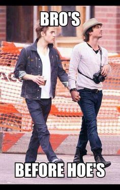 two young men walking down the street with construction cones in the back ground behind them