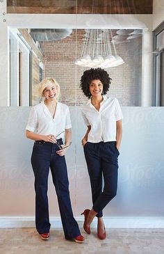 two women standing next to each other in front of a window