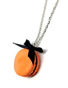 an orange necklace with a black bow on it's end and two pieces of cake in the middle