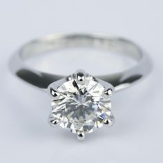 a round brilliant cut diamond set in a white gold soltation ring, on a plain surface