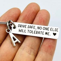 a hand holding a silver key chain that says drive safe, no one else will tolerate me