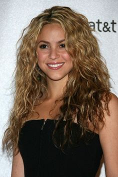 a beautiful young blonde woman with long curly hair smiling and posing for the camera at an event