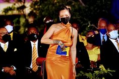 a woman in an orange dress wearing a face mask