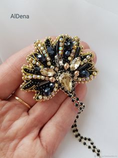 a hand holding a black and gold brooch